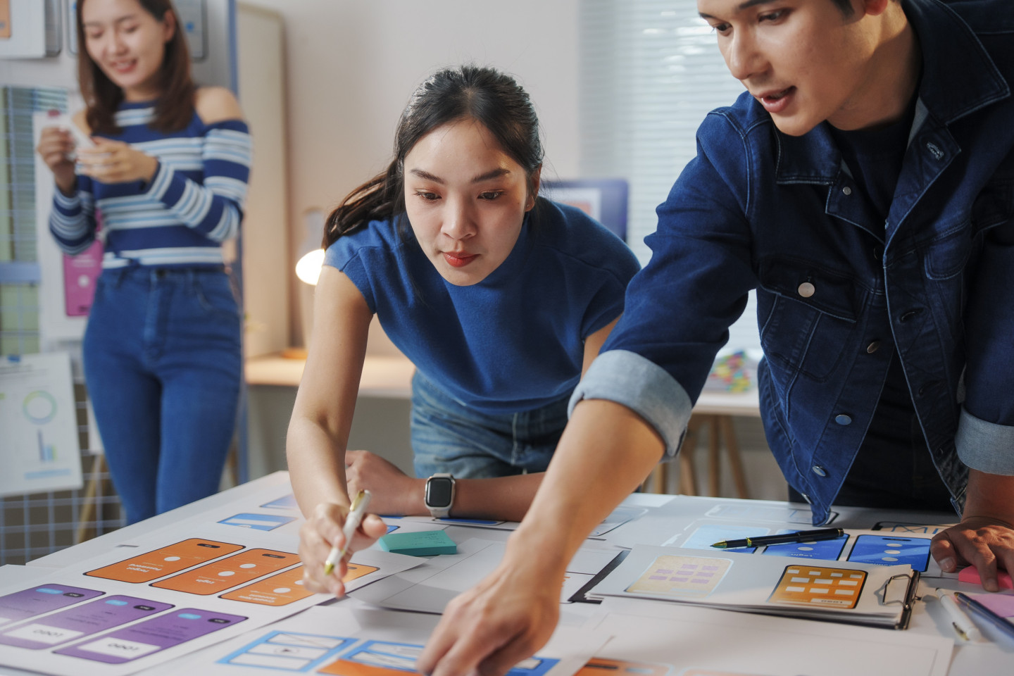 young-asian-ux-ui-designers-working-together-on-a-new-mobile-app-interface-discussing-user-experience-and-user-interface-elements